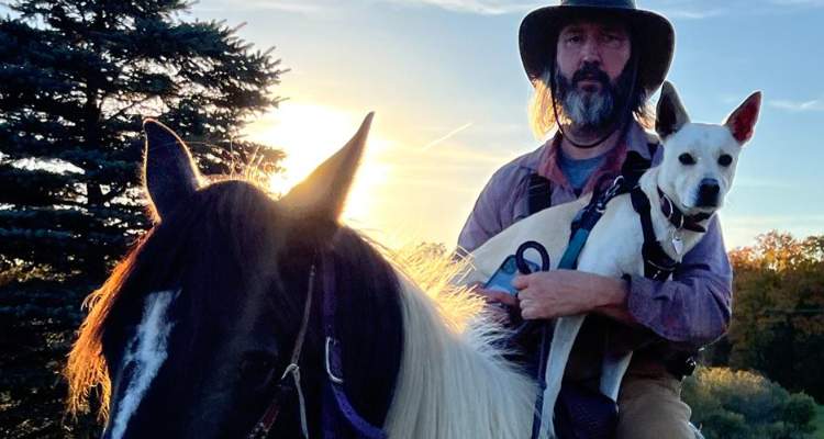 Tom Green riding a horse along with his pet.